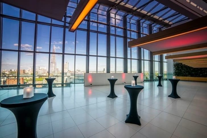 The venue at dusk, poseur tables along a glass wall with the Shard beyond.